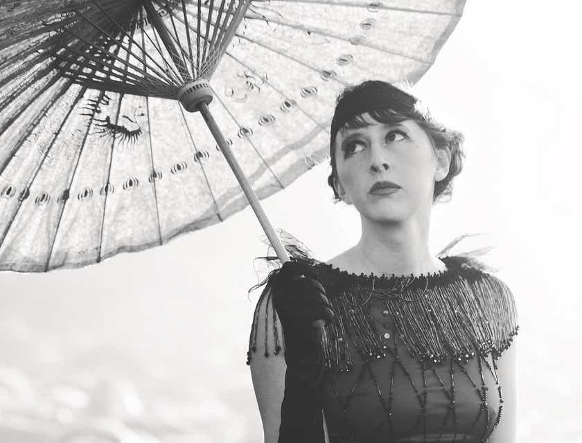 Zdjęcie kobiety w stroju w stylu lat 20. trzymającej parasolkę.