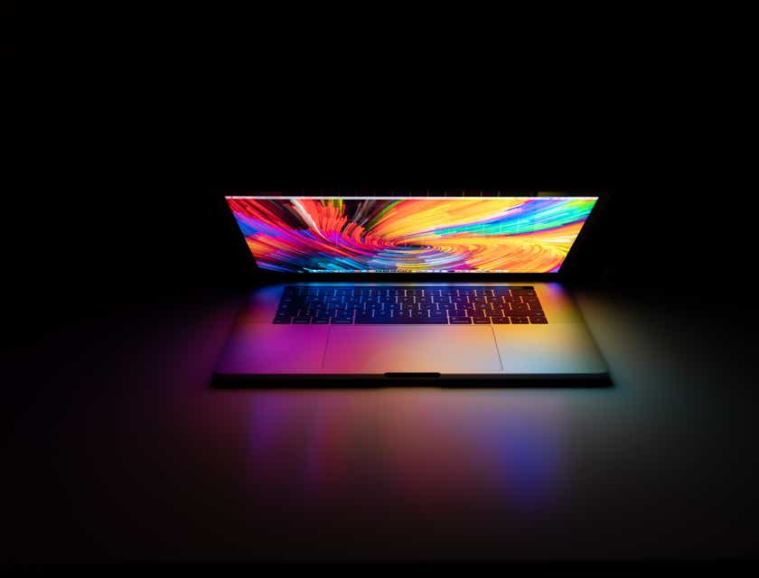 Rozświetlony laptop MacBook Pro w ciemnym pokoju firmy z komputerami.