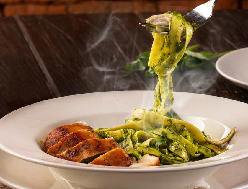 Pasta z zielonym pesto i plastrami kurczaka podawana w restauracji włoskiej.