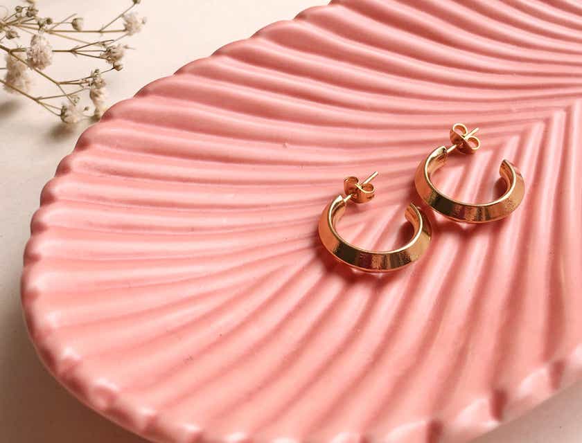 Gouden oorbellen op een geribbeld, roze schaaltje.