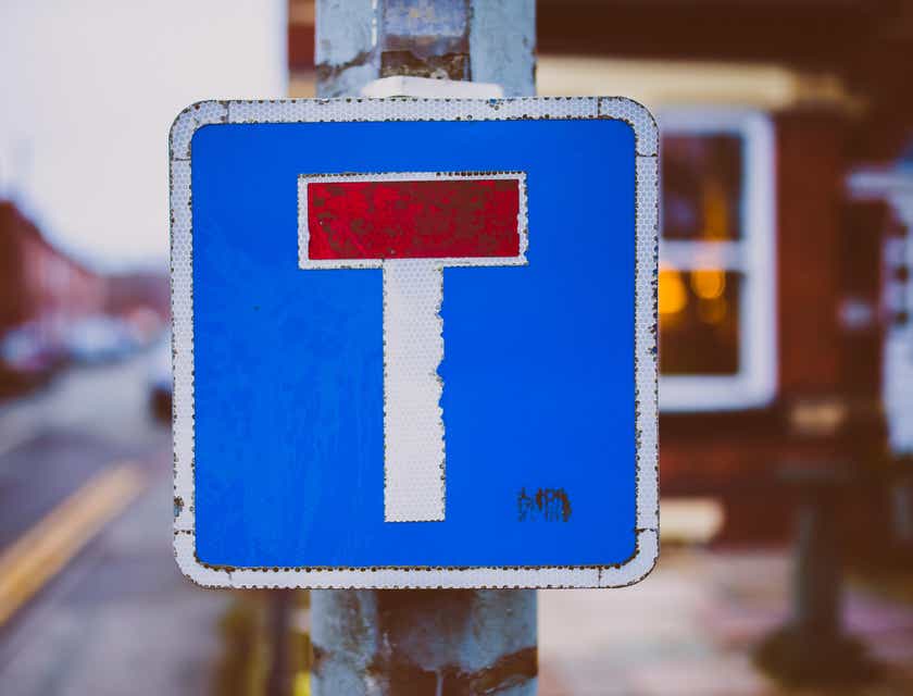 A blue, white, and red road sign that resembles the letter "T."