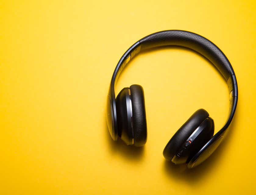 Schwarze Kopfhörer liegen auf einer gelben Oberfläche.