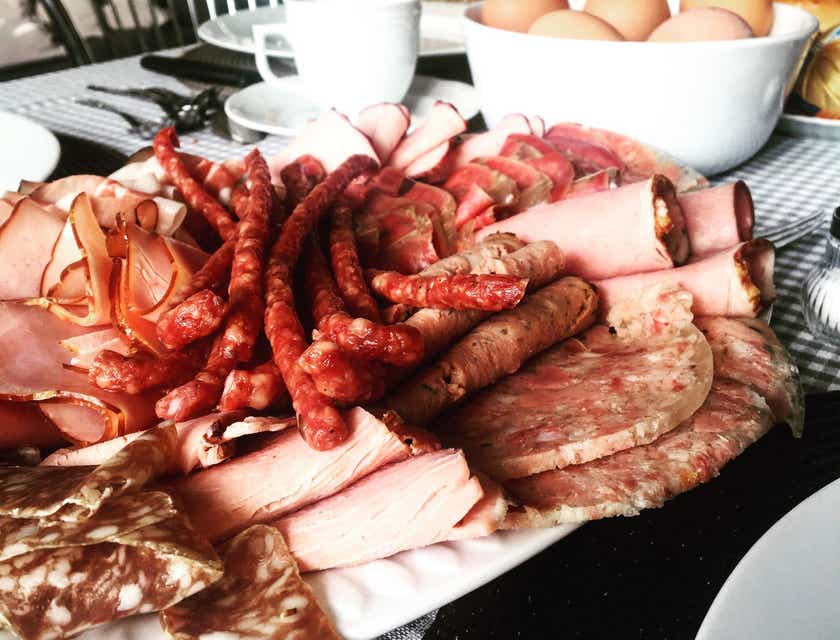 Prato com cortes de carnes defumadas sobre uma mesa em uma charcutaria.