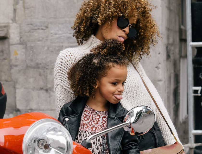 Mãe e filha fazendo caretas atrevidas no espelho de uma moto.