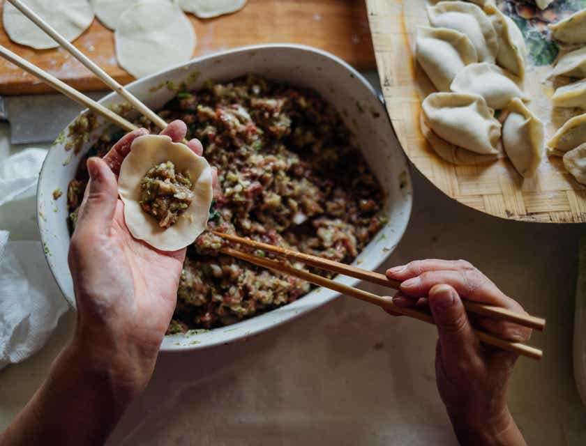 Uma pessoa preparando comida chinesa usando pauzinhos.