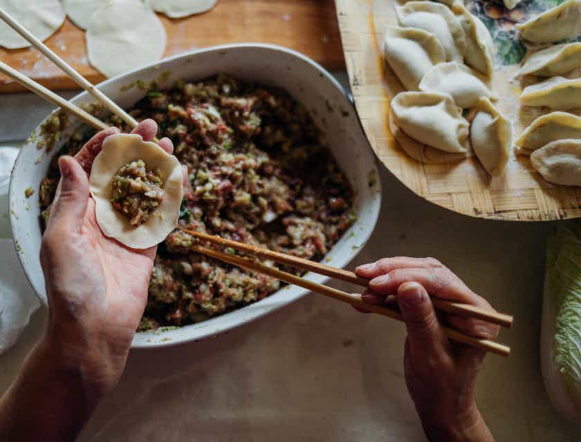 Eine Person füllt chinesische Dumplings mithilfe von Essstäbchen.