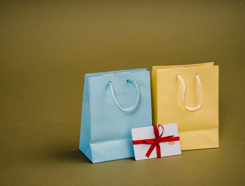 Um cartão-presente cuidadosamente embrulhado ao lado de duas sacolas de presentes.