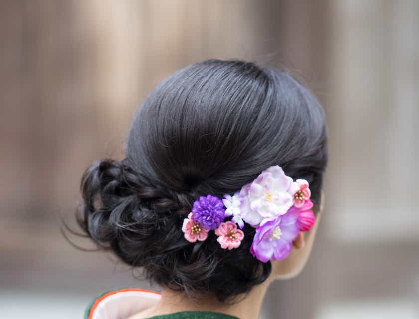 Eine Frau trägt einen femininen Blumenschmuck im dunklen Haar.