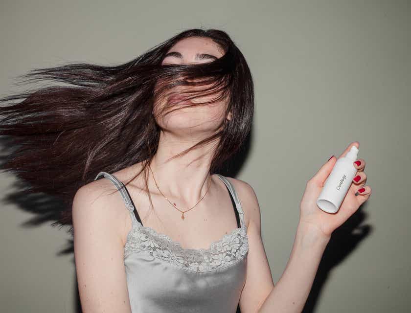 Una persona con i capelli lunghi che tiene in mano un prodotto per la cura dei capelli.