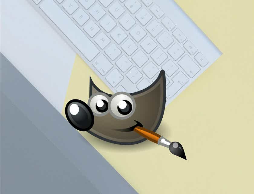 El logo del programa GIMP en un escritorio con un teclado y una tableta de dibujo.