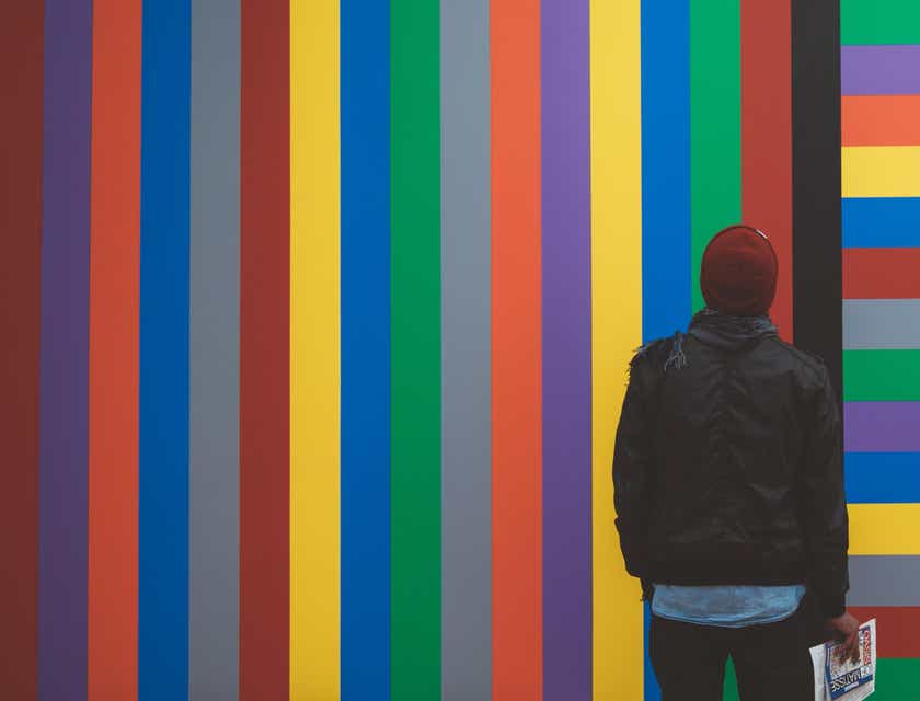 Ein Mann schaut sich eine mit bunten Streifen verzierte Wand an.