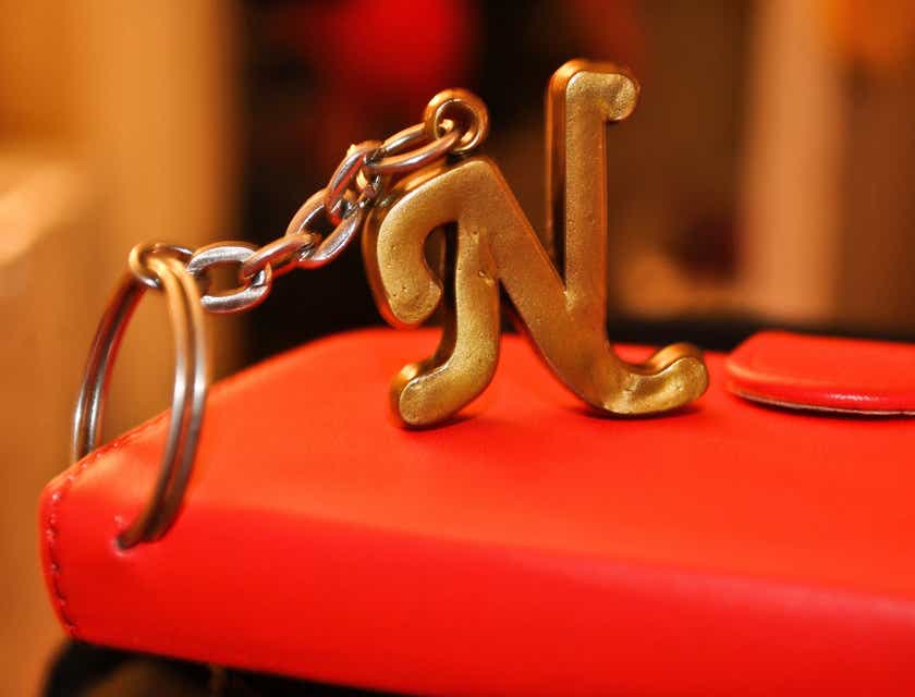 Gantungan kunci berbentuk huruf N yang terpasang pada dompet merah.