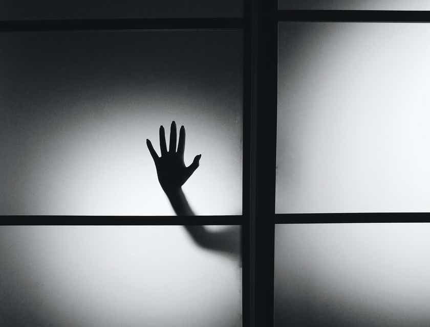 Una mano inquietante di una creatura paranormale che preme contro una finestra.