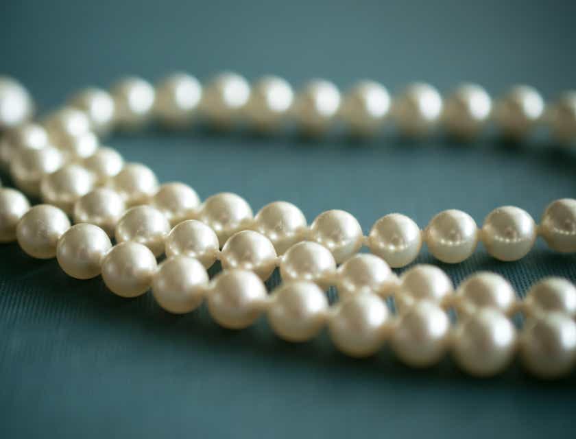 Un collier de perles nacrées sur une surface bleue.