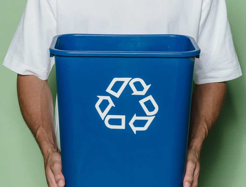Seorang pria memegang tempat sampah daur ulang berwarna biru.