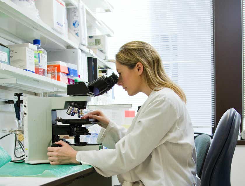 Une scientifique examine un spécimen sous un microscope dans un laboratoire scientifique.