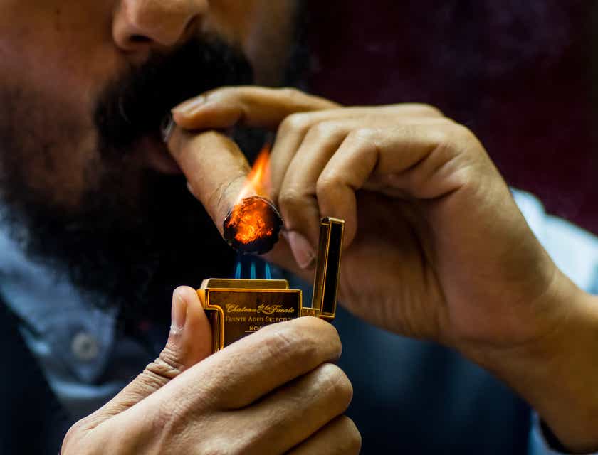 Mężczyzna podpalający cygaro zakupione w sklepie tytoniowym.