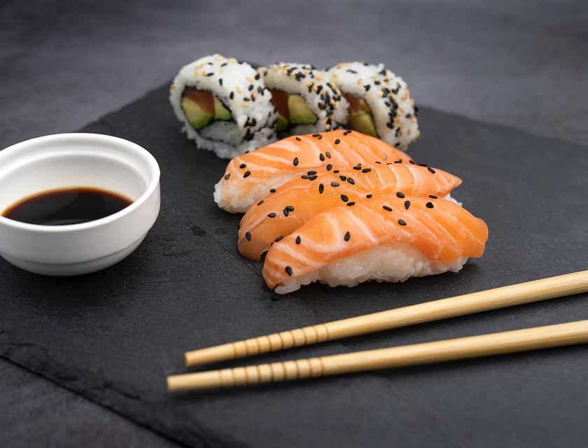 Um prato de sushi com pauzinhos e shoyu.