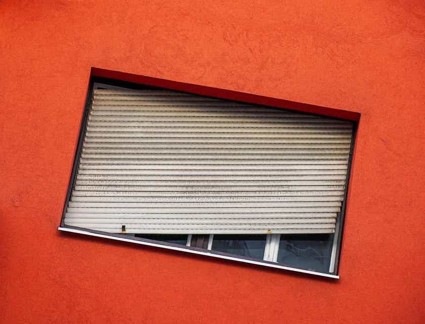 Eine orange Mauer und ein geneigtes Fenster vermitteln eine ungewöhnliche Perspektive.