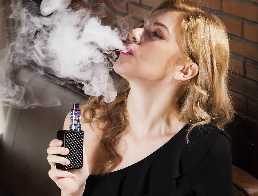 A woman exhaling smoke from a vape.
