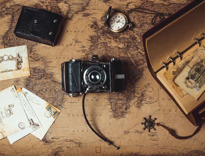 Des objets vintage, dont un appareil photo, des cartes postales et une montre, exposés sur une vieille carte.