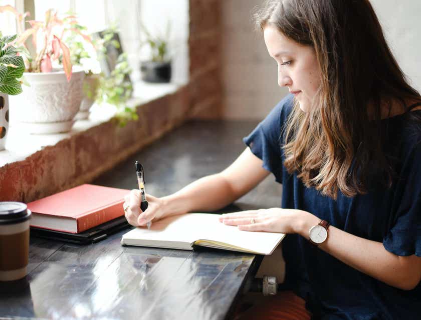Una mujer escribiendo en su cuaderno en una cafetería.