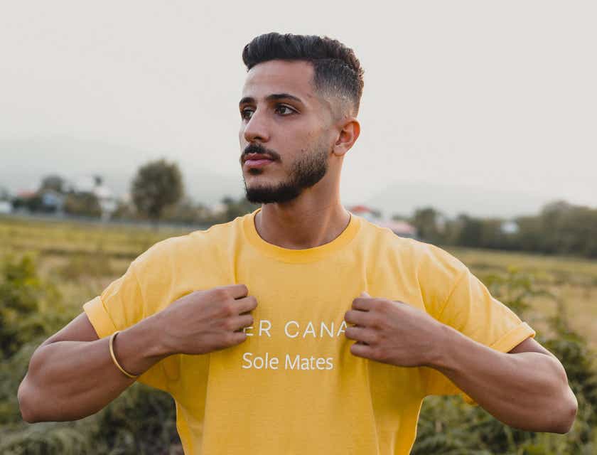 Um homem em um campo usando uma camiseta amarela.