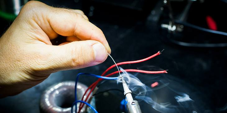 An appliance repair technician soldering wires.