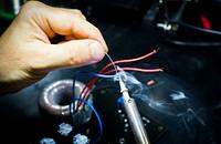 An appliance repair technician soldering wires.