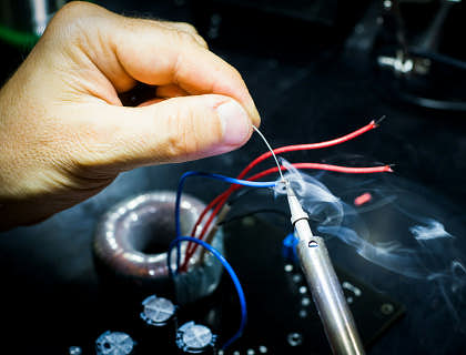 An appliance repair technician soldering wires.