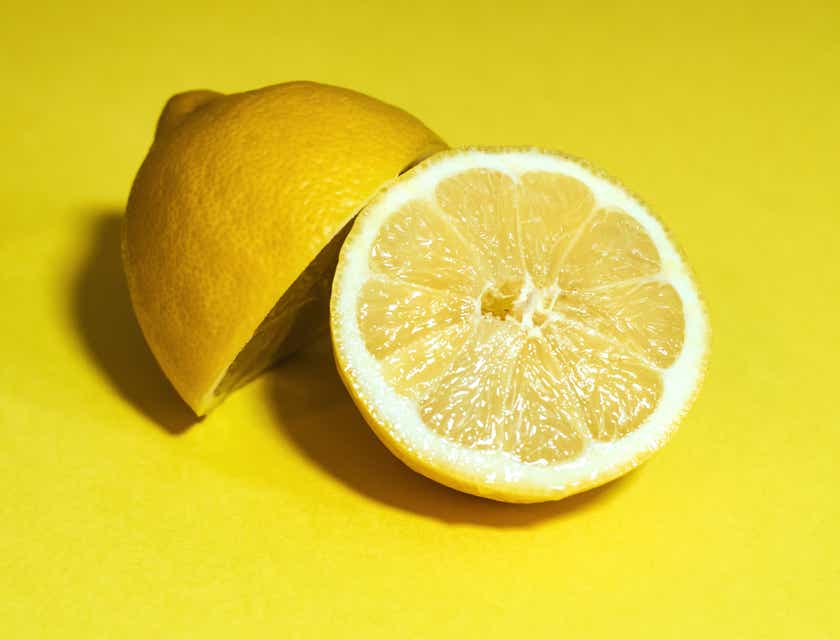 Een doorgesneden citroen tegen een gele achtergrond.