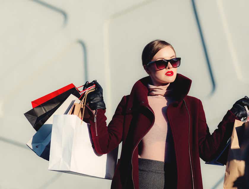 Una mujer muy chic posando con bolsas de compras.
