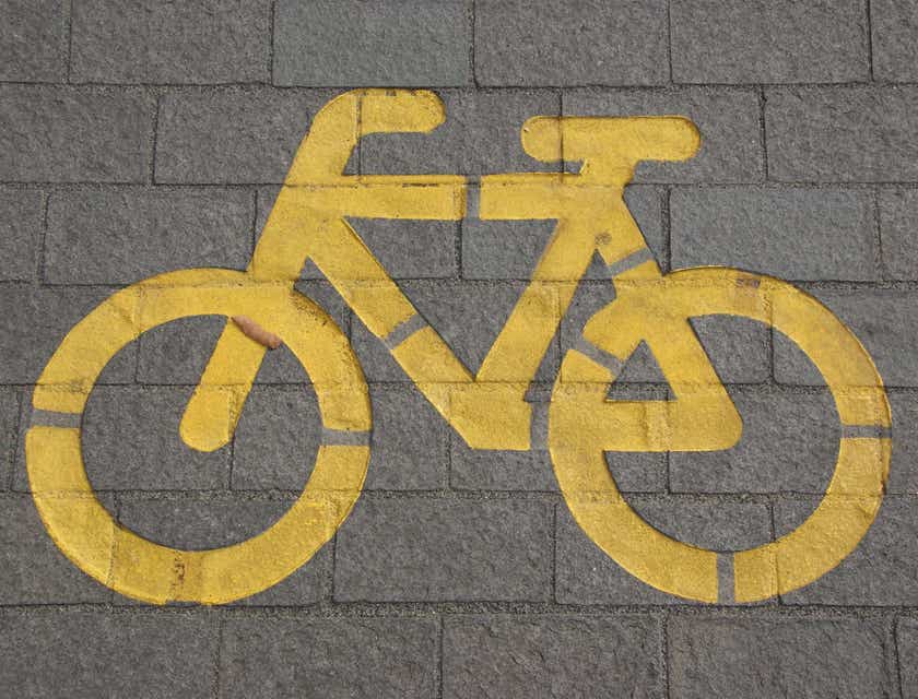 Een 2D-tekening van een gele fiets op een grijze muur.