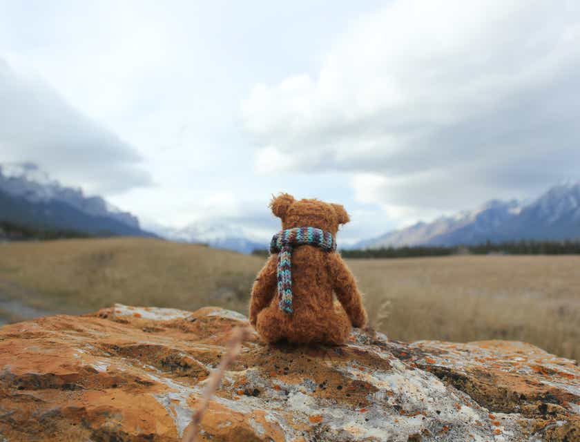 Boneka teddy bear yang menggemaskan sedang menikmati pemandangan gunung.