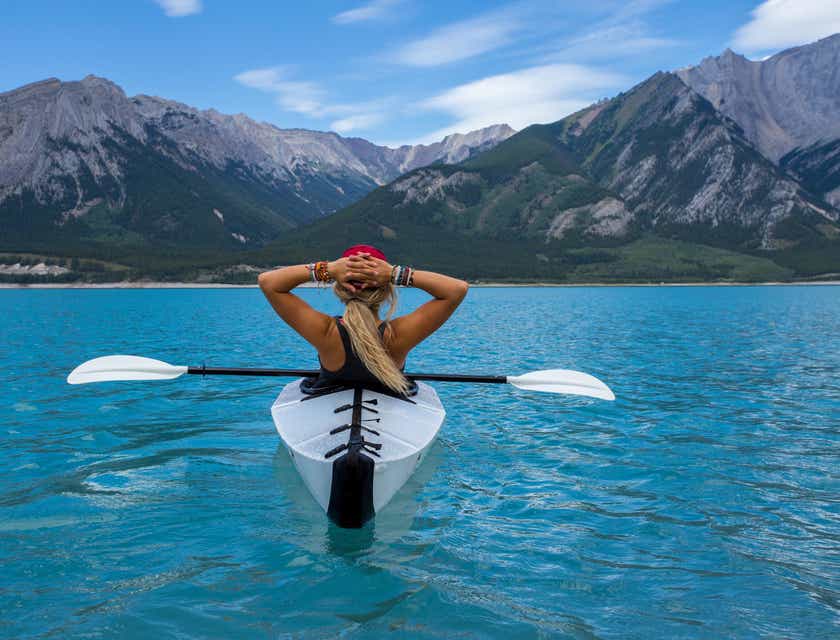 Una persona che fa kayak intenta ad ammirare il panorama durante uno stop nel suo viaggio avventuroso.