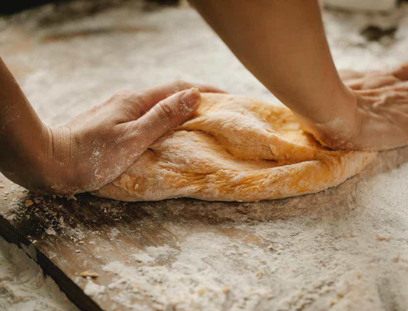 Un artisan pétrissant un pain à deux mains.