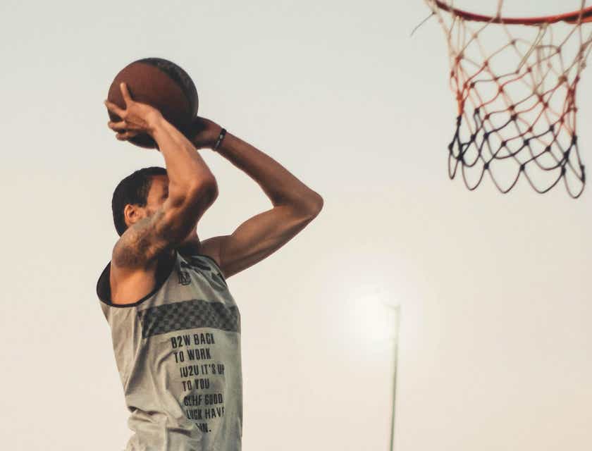 Un jugador de basketball salta en el aire para anotar una canasta.