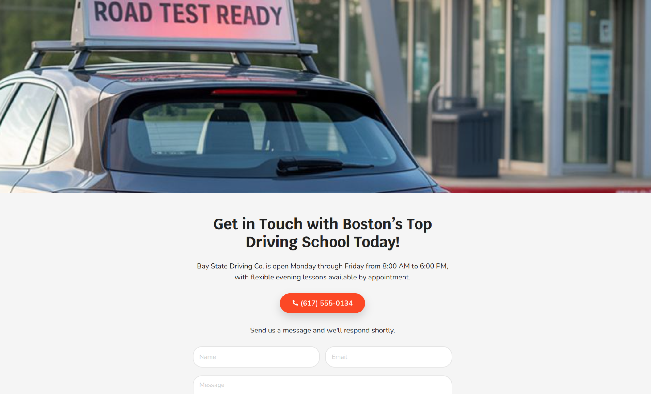 Bay State Driving Co. contact section with a rear view of a parked car displaying a “ROAD TEST READY” roof sign above the heading “Get in Touch with Boston’s Top Driving School Today!” and a red button showing the phone number