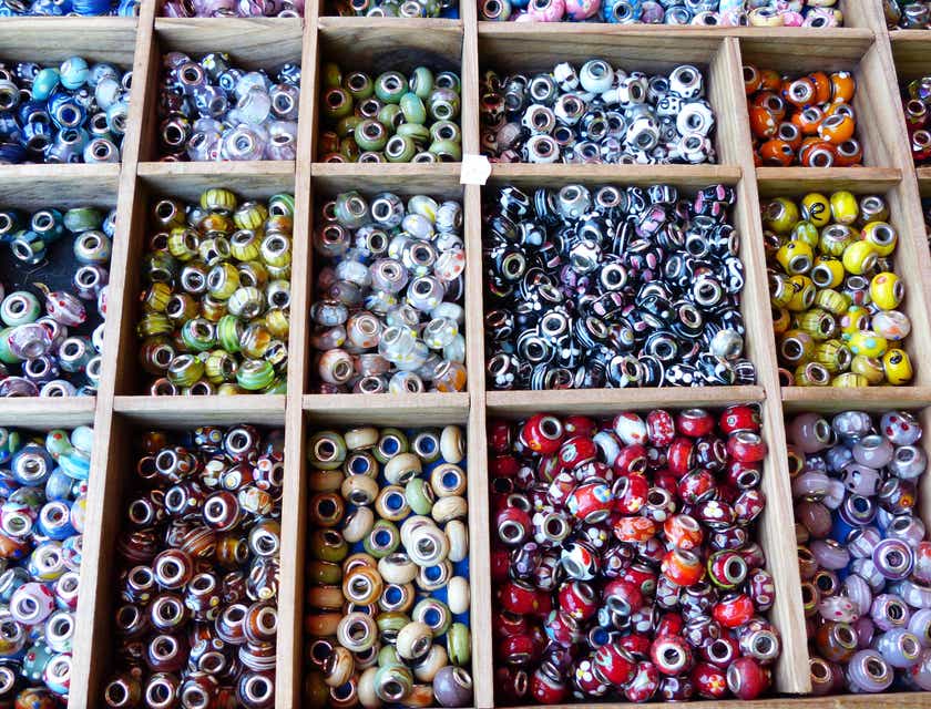 Des perles de verre assorties présentées dans un plateau en bois dans un magasin de perles.
