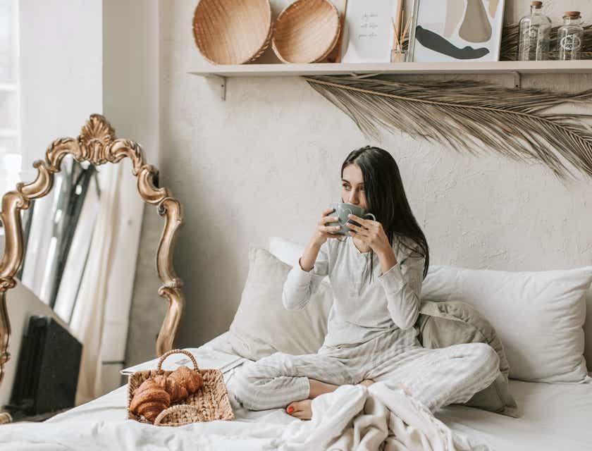 Una donna che beve del caffè nel letto di un bed and breakfast.