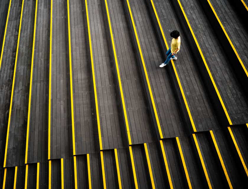 Seseorang sedang berjalan menuruni tangga hitam dan kuning.