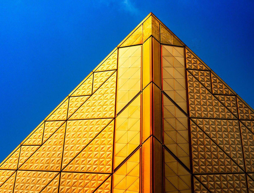 Une pyramide dorée sur un ciel bleu.