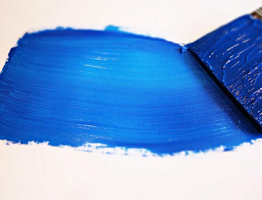 Un pennello che passa una vernice blu sopra una superficie bianca.