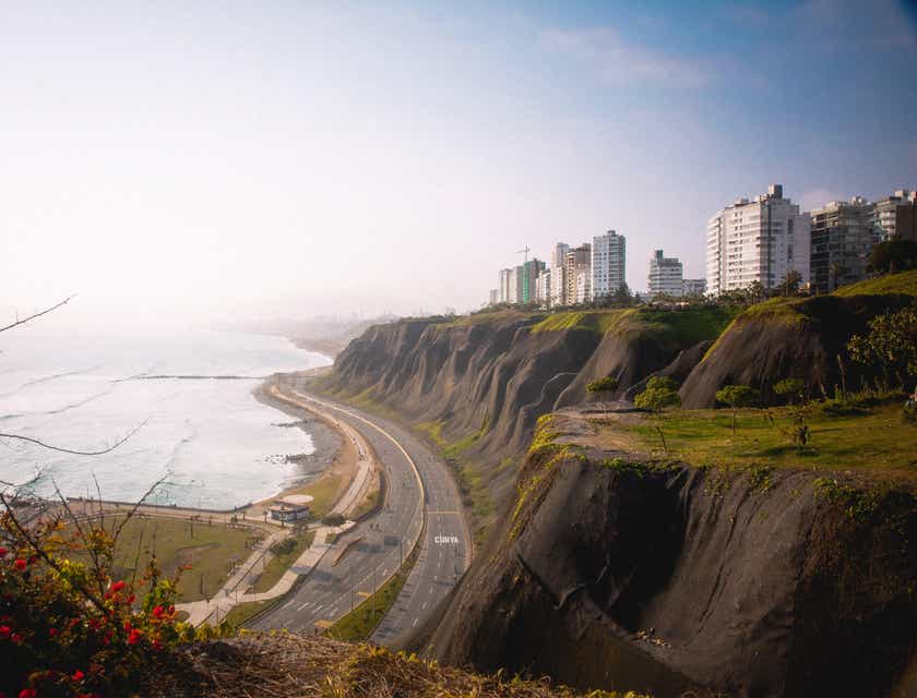 Imagen de edificios a la orilla de un acantilado, con una carretera debajo a la orilla del mar en Lima, Perú.