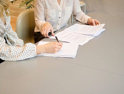 Man at a desk writing a business proposal on a white piece of paper