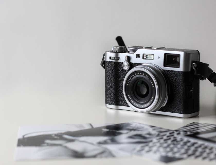 A camera neatly displayed on a white surface next to black and white photographs.