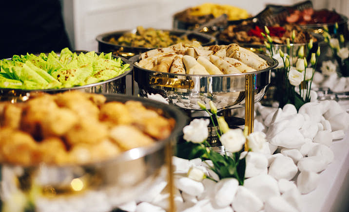 A buffet table with various food dishes set up by a catering company.