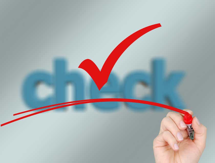 Una mano dibujando una marca de verificación roja en una placa de vidrio en un logo con check.
