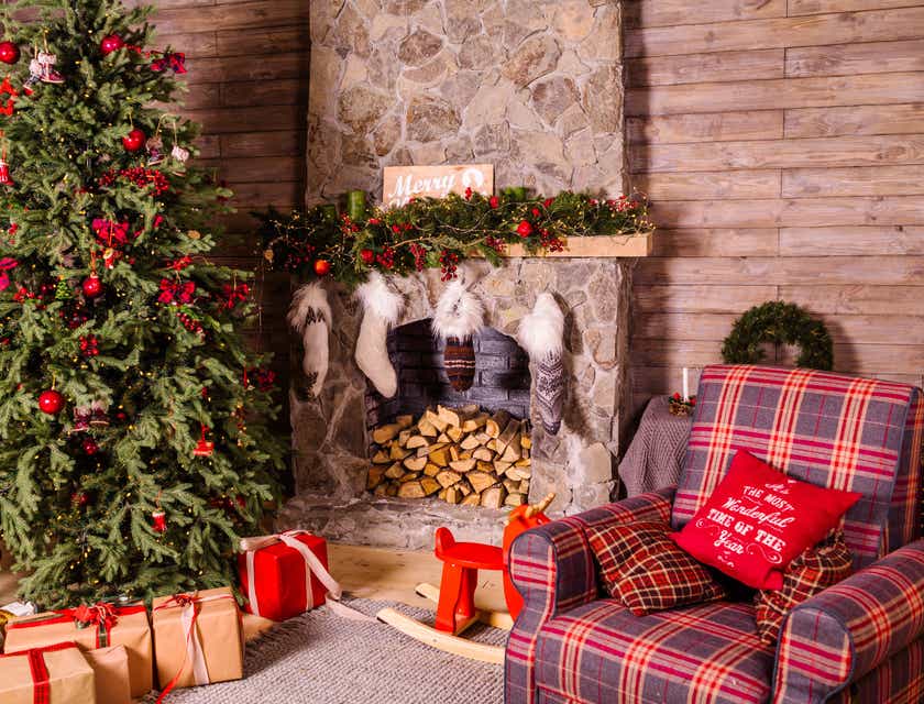 Sebuah pohon Natal dengan berbagai hadiah dan kaus kaki di sebuah ruangan dengan perapian.