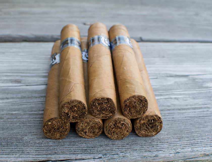 Una pila de puros exhibidos en una superficie de madera en un logo para puros.